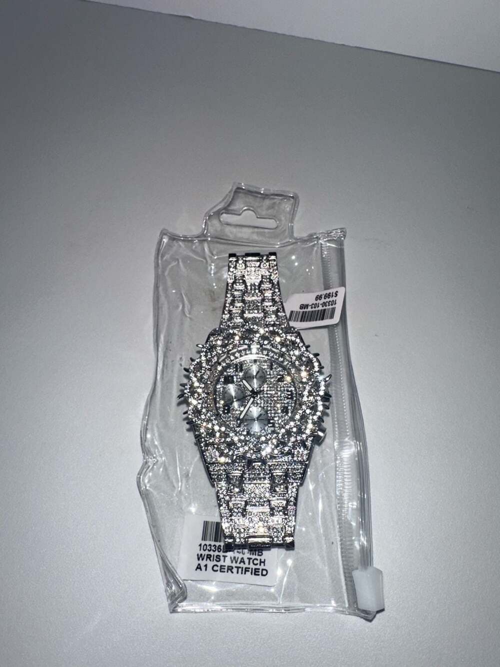 Iced out silver-tone wrist watch with chronograph style face.